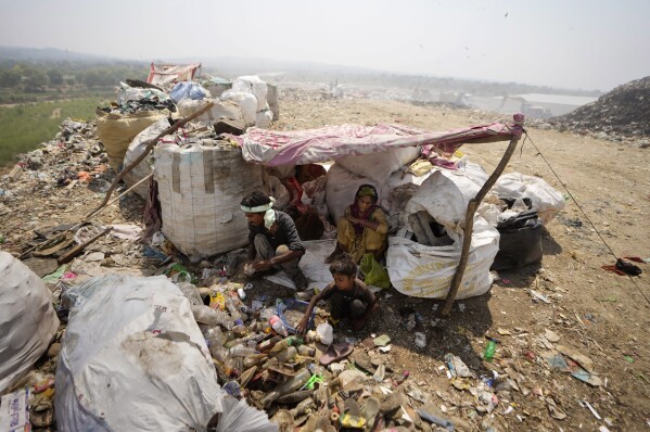 Waste pickers Arjun, 6, sorts recyclable items with his parents at a garbage dump site during a heat wave on the outskirts of Jammu, India, Thursday, June 19, 2024. As many as 4 million people in India scratch out a living searching through landfills for anything they can sell. (AP Photo/Channi Anand)