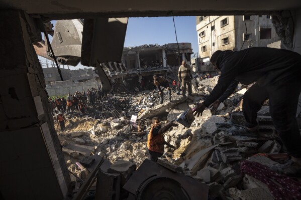 Palestinians search for bodies and survivors in the rubble of a residential building destroyed in an Israeli airstrike, in Rafah, southern Gaza Strip, Tuesday, Dec. 19, 2023. (AP Photo/Fatima Shbair)