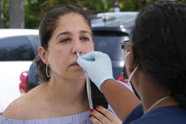 Raquel Heres gets a COVID-19 rapid test to be able to travel overseas, Saturday, July 31, 2021, in North Miami, Fla. Federal health officials say Florida has reported 21,683 new cases of COVID-19, the state's highest one-day total since the start of the pandemic. The state has become the new national epicenter for the virus, accounting for around a fifth of all new cases in the U.S. Florida Gov. Ron DeSantis has resisted mandatory mask mandates and vaccine. (AP Photo/Marta Lavandier)