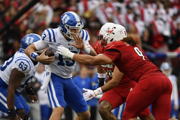 Duke quarterback Riley Leonard (13) is hit by Louisville defensive lineman Ashton Gillotte (9) during the first half of an NCAA college football game in Louisville, Ky., Saturday, Oct. 28, 2023. (AP Photo/Timothy D. Easley)