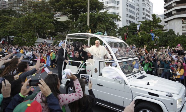 FILE - Pope Francis waves to people from his popemobile along the Copacabana beachfront as he arrives for the Stations of the Cross procession in Rio de Janeiro, Brazil, Friday, July 26, 2013. When Pope Francis made the first foreign trip of his papacy, to Rio de Janeiro for World Youth Day in 2013, he urged young people to make a "mess" in their local churches, to shake things up even if it ruffled the feathers of their bishops. (AP Photo/Andre Penner, File)