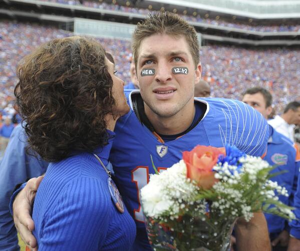FILE - Florida quarterback Tim Tebow embraces his mother, Pam, during a pregame ceremony for graduating seniors on the Florida football team prior to an NCAA college football game against Florida State in Gainesville, Fla., Nov. 28, 2009. While its Super Bowl commercial appearances are few, religion – Christianity especially – is entrenched in football culture.(AP Photo/Phil Sandlin, Pool, File)