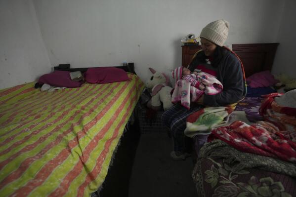 Single mother Tania Herrera holds her 20-day-old daughter Sara Milena as she breastfeeds her in the one-room shack where they live with her parents in Quito, Ecuador, Monday, Nov. 15, 2022. Herrara's parents are the breadwinners and earn $5 to $7 a day to feed five adults and support the new arrival. That income is stretched in hopes of feeding the adults twice a day: coffee with bread, when there is any, in the morning and a plate of rice at night, or maybe not. (AP Photo/Dolores Ochoa)