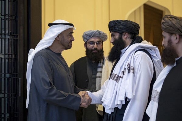2024年6月4日，星期二，在阿拉伯联合酋长国阿布扎比的沙提宫，阿联酋官方WAM通讯社发布的这张照片中，阿布扎比统治者谢赫·穆罕默德·本·扎耶德·阿勒纳哈扬（左）与塔利班官员西拉朱丁·哈卡尼（Sirajuddin Haqqani）握手。阿联酋领导人星期二会见了塔利班政府的一名官员，美国仍在通缉他，悬赏他1000万美元，因为他参与了一起导致一名美国公民死亡的袭击和其他袭击。（WAM通过AP）