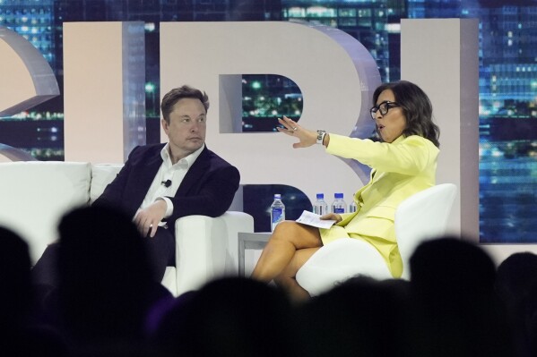 FILE - Elon Musk, left, speaks with Linda Yaccarino, April 18, 2023, in Miami Beach, Fla. The new CEO of the company formerly known as Twitter says she's spent much of the past eight weeks trying to get big brands back to advertising on the social media platform that's been in upheaval since it was bought last year by Musk. X Corp. CEO Linda Yaccarino said Thursday, Aug. 10 on CNBC that she been focused on talking with brands like Coca Cola, Visa and State Farm. (AP Photo/Rebecca Blackwell, File)