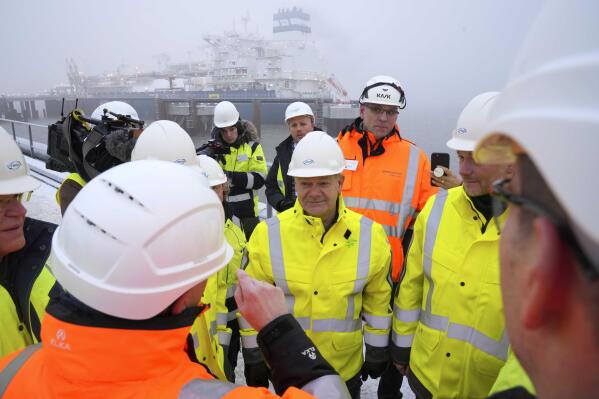 German Chancellor Olaf Scholz, center, listens during an event in front of the 'Hoegh Esperanza' Floating Storage and Regasification Unit (FSRU) during the opening of the LNG (Liquefied Natural Gas) terminal in Wilhelmshaven, Germany, Saturday, Dec. 17, 2022. (AP Photo/Michael Sohn, pool)