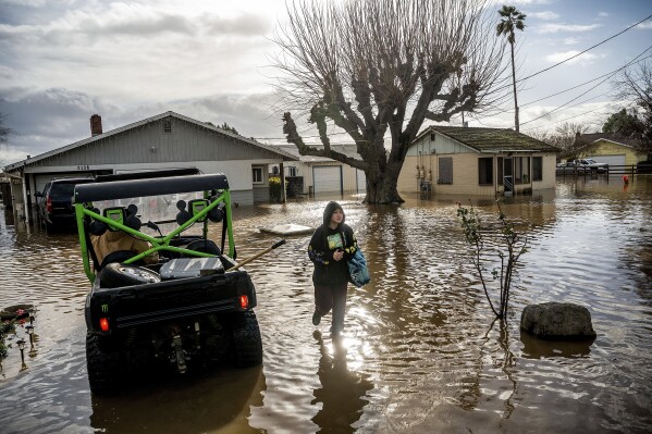 FILE - Brenda Ortega, 15, salvages items from her flooded Merced, Calif., home on Jan. 10, 2023. Flood risk and climate change are pushing millions of people to move from their homes, according to a new study by the risk analysis firm First Street Foundation. (AP Photo/Noah Berger, File)