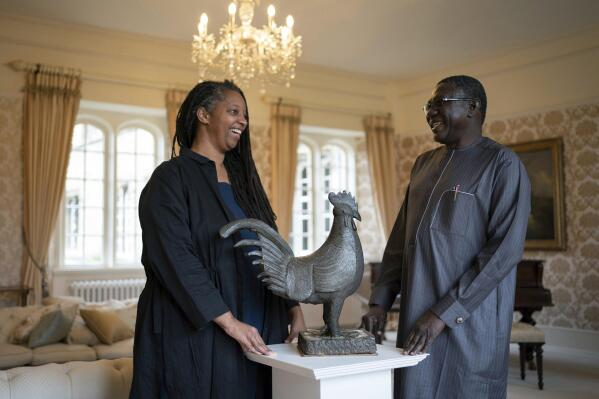 Master of Jesus College Sonita Alleyne, left and  Director General of Nigeria's National Commission for Museums and Monuments Professor Abba Isa Tijani pose for a photo ahead of a ceremony at Jesus College Cambridge, where the looted bronze cockerel, known as the Okukur, will be returned to Nigeria, in Cambridge, England, Wednesday, Oct. 27, 2021.  Jesus College announced in 2019 that it would return the Okukor, a statue that was taken from the Court of Benin in what is now Nigeria by British colonial forces in 1897.  (Joe Giddens/PA via AP)