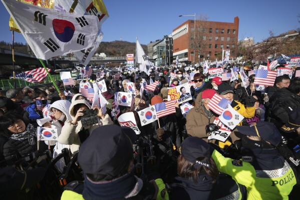 Supporters of impeached South Korean President Yoon Suk Yeol stage a rally after hearing a news that a court issued warrants to detain Yoon, near the presidential residence in Seoul, South Korea, Tuesday, Dec. 31, 2024. The letters read "Oppose Impeachment." (AP Photo/Lee Jin-man)