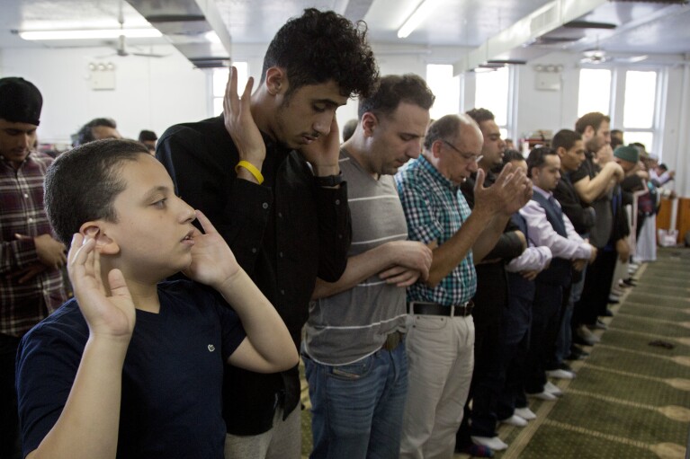 FILE - Men and children attend a prayer service at Masjid Al-Farooq for the Muslim holiday of Eid al-Fitr, Friday, June 15, 2018, in the Brooklyn borough of New York. (AP Photo/Mark Lennihan, File)