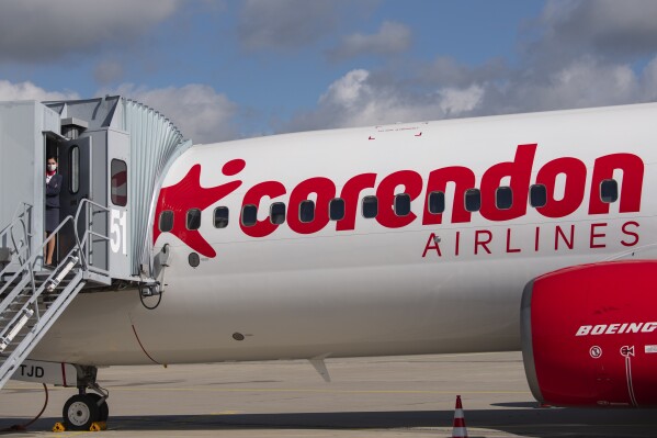 FILE - Senior cabin crew member Magdalini Michailidou stands on the gangway prior the first holiday flight of the Corendon Airlines Europe to the Greek destination Rhodos at the airport Erfurt-Weimar in Erfurt, Germany, July 2, 2020. Corendon Airlines says that it will sell an adults-only zone — no one under 16 allowed — on flights between Amsterdam and Curacao starting in November 2023. The Turkish carrier says people traveling without children will get quiet surroundings, and parents won't have to worry that their crying or fidgeting kids will annoy fellow passengers. (AP Photo/Jens Meyer, File)