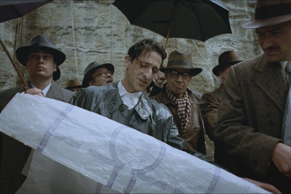 This image released by A24 shows Adrien Brody, center, in a scene from "The Brutalist." (Lol Crawley/A24 via AP)