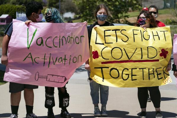 San Pedro High School students hold vaccination signs at a school-based COVID-19 vaccination event for students 12 and older in San Pedro, Calif., Monday, May 24, 2021. Schools are turning to mascots, prizes and contests to entice youth ages 12 and up to get vaccinated against the coronavirus before summer break. (AP Photo/Damian Dovarganes)