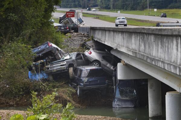 Cars are stacked on top of each other on the banks of Blue Creek being swept up in flood water, Monday, Aug. 23, 2021, in Waverly, Tenn. Heavy rains caused flooding in Middle Tennessee days ago and have resulted in multiple deaths as homes and rural roads were washed away. (AP Photo/John Amis)
