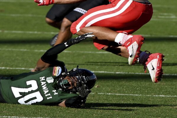 Houston running back Kyle Porter (22) leaps over a tackle attempt by Hawaii defensive back Cameron Lockridge (20) in the second quarter of the New Mexico Bowl NCAA college football game in Frisco, Texas, Thursday, Dec. 24, 2020. (AP Photo/Matt Strasen)