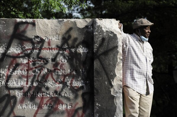 Robert Walker poses for a photograph on the remains of a Confederate memorial that was removed overnight in Birmingham, Ala., on Tuesday, June 2, 2020. The city took down the more than 50-foot-tall obelisk following protests over the police death of George Floyd and a night of vandalism in the city. (AP Photo/Jay Reeves)