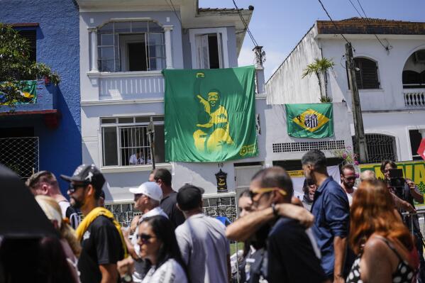 A banner Pele hangs on a home where people line up to pay their last respects to the late Brazilian soccer great who lies in state at Vila Belmiro stadium in Santos, Brazil, Monday, Jan. 2, 2023. (AP Photo/Matias Delacroix)