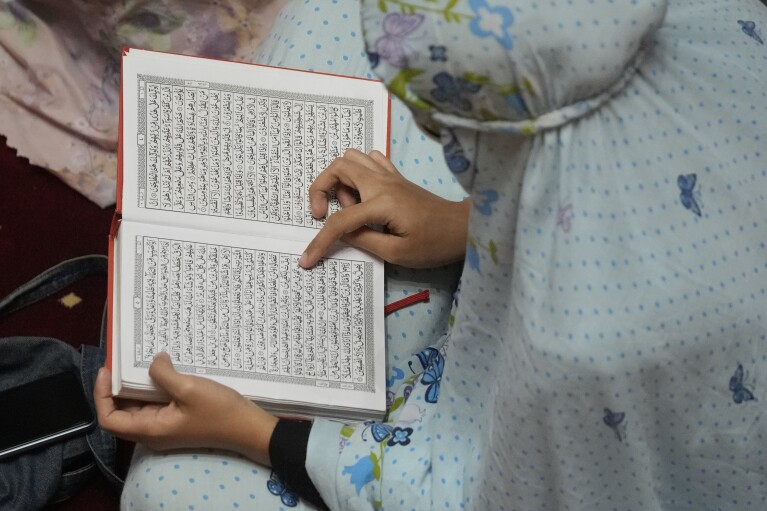 A Muslim woaman reads Quran during an evening prayer called 'tarawih' marking the first eve of the holy fasting month of Ramadan, at Istiqlal Mosque in Jakarta, Indonesia, Monday, March 11, 2024. (AP Photo/Dita Alangkara)