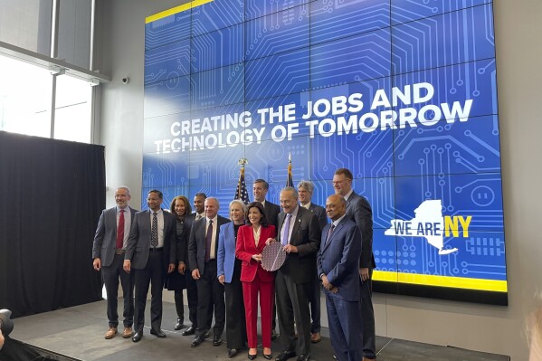 New York Gov. Kathy Hochul and Sen. Chuck Schumer hold a silicon wafer and pose for a photo with lawmakers and leaders from the semiconductor industry during an event at University at Albany in Albany, New York, Monday, Dec. 11, 2023. New York will spend $1 billion to expand research into chip technology in Albany, the state's capital, with the goal of turning the region into a global center of semiconductor research and manufacturing, Gov. Kathy Hochul announced Monday. (AP Photo/Maysoon Khan)