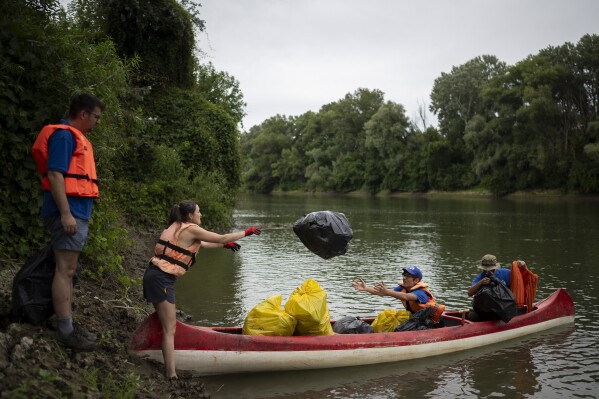 Voluntários coletam lixo nas margens do rio Tisza, perto de Tiszaroff, Hungria, terça-feira, 1º de agosto de 2023. (AP Photo/Denes Erdos)