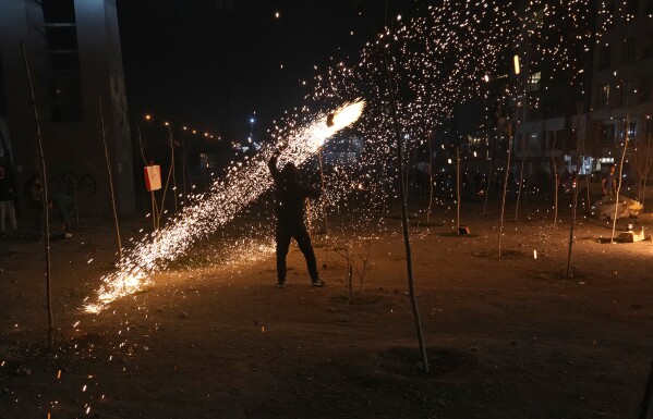 An Iranian man plays with a firework celebrating Chaharshanbe Souri, or Wednesday Feast, an ancient Festival of Fire on the eve of the last Wednesday of the Persian year, in Tehran, Iran, Tuesday, March 18, 2025. (AP Photo/Vahid Salemi)