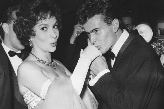 FILE - German actor Horst Buchholz kisses the hand of Italian actress Gina Lollobrigida, during the International Film Festival (Berlinale) in Berlin, Germany, July 5, 1958. (AP Photo/Werner Kreusch, File) Lollobrigida has died in Rome at age 95. Italian news agency Lapresse reported Lollobrigida’s death on Monday, Jan. 16, 2023 quoting Tuscany Gov. Eugenio Giani. (AP Photo/Werner Kreusch, File)