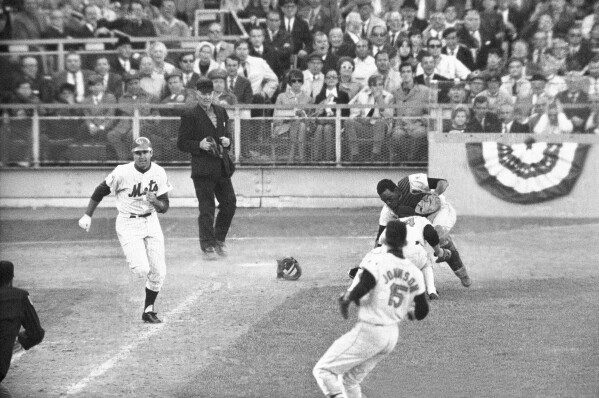 FILE -Orioles catcher Ellie Hendricks and pitcher Pete Richert reach for bunt laid down by J.C. Martin in tenth inning of game 4 of the World Series baseball game Oct. 15, 1969 in New York. Richert fielded it and his throw to Dave Johnson hit Martin in back and bounded away, enabling Rod Gaspar to score from second. Umpire is Shag Crawford. Major League Baseball is widening the runner's lane approaching first base to include a portion of fair territory, shortening the pitcher's clock with runners on base by two seconds to 18 and further reducing mound visits in an effort to further speed games next season.(AP Photo/File)