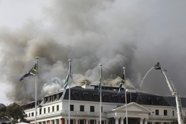 FILE - Smoke rises from the Parliament in Cape Town, South Africa, Monday, Jan 3, 2022 after the fire re-ignited late afternoon. A man charged with terrorism and other offenses over a 2022 fire that badly damaged South Africa’s historic Parliament complex in Cape Town has been declared unfit to stand trial. Zandile Mafe was diagnosed with schizophrenia by an expert panel in a report and a judge in the Western Cape High Court ruled Monday, Dec. 11, 2023, that he agreed with the report. (AP Photo/Nardus Engelbrecht, File)