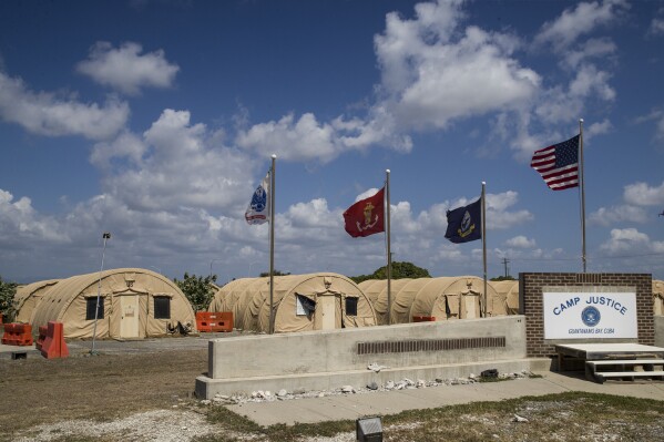 FILE - In this photo reviewed by U.S. military officials, flags fly in front of the tents of Camp Justice in Guantanamo Bay Naval Base, Cuba, on April 18, 2019. For the first time since the facility in Cuba opened in 2002, a U.S. president had allowed a United Nations independent investigator, Fionnuala Ní Aoláin, to visit. (AP Photo/Alex Brandon, File)