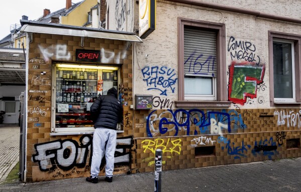 A man waits at a former water house, a small shop that sprung up in the 19th century to encourage workers to drink affordable water rather than beer or schnapps, that is now a kiosk in Frankfurt, Germany, on Feb. 15, 2025. (AP Photo/Michael Probst)
