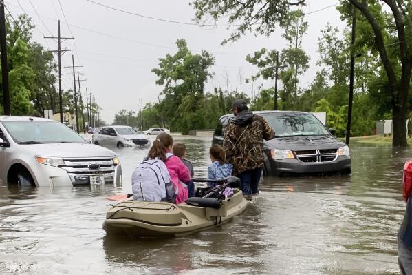 Parents use boats to pick up students from schools after nearly a foot of rain fell in Lake Charles, La., Monday, May 17, 2021. (Rick Hickman/American Press via AP)