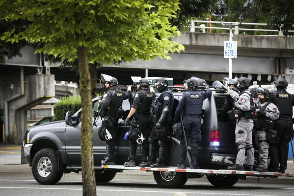 Portland Police prepare to head towards Tom McCall Waterfront Park as right-wing groups and counterprotesters gathered in downtown Portland, Ore., on Saturday, Aug. 17, 2019.  Flag-waving members of the Proud Boys and Three Percenters militia group began gathering late in the morning, some wearing body armor and helmets. Meanwhile black clad, helmet and mask-wearing anti-fascist protesters — known as antifa — were also among the several hundred people on the streets. (AP Photo/Moriah Ratner)