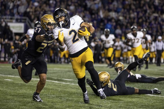 Appalachian State wide receiver Kaedin Robinson (2) tries to outrun James Madison safety Jacob Thomas (27) after shedding cornerback Chauncey Logan (2) and linebacker Noah Holmes, right, on his way to scoring the game-winning touchdown during overtime of an NCAA college football game in Harrisonburg, Va., Saturday, Nov. 18, 2023. (Daniel Lin/Daily News-Record via AP)