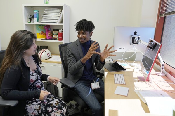 Post-doctoral researcher Tofunmi Omiye, right, gestures while talking in his office with assistant professor Roxana Daneshjou at the Stanford School of Medicine in Stanford, Calif., Tuesday, Oct. 17, 2023. A new study led by Stanford researchers cautions that popular chatbots are perpetuating racist, debunked medical ideas, prompting concerns that the tools could worsen health disparities for Black patients. Omiye co-led the study and Daneshjou was a faculty advisor. (AP Photo/Eric Risberg)