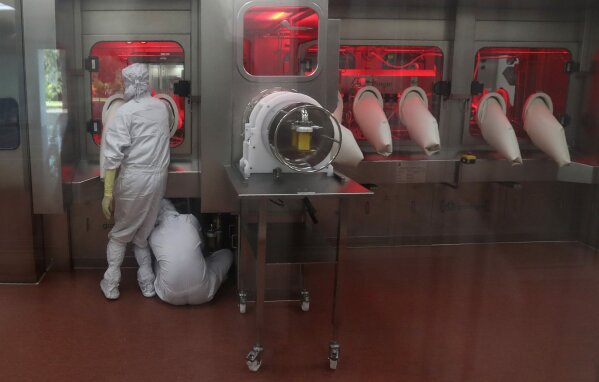 Employees operate a filling machine inside a laboratory at the Serum Institute of India, in Pune, India, Thursday, Jan. 21, 2021. India said Tuesday, April 13, that it will approve the use of all coronavirus vaccines that have been given an emergency nod by the World Health Organization or regulators in the United States, Europe, Britain or Japan. India had already given the nod to the AstraZeneca vaccine and another one made by Indian vaccine maker Bharat Biotech. (AP Photo/Rafiq Maqbool)
