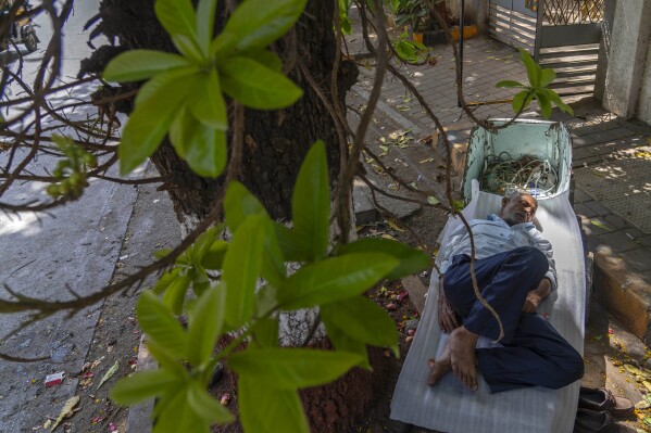 A laborer sleeps on a handcart in the shade of a tree during a hot summer day in Mumbai, India, Thursday, May 2, 2024. (Ǻ Photo/Rafiq Maqbool)