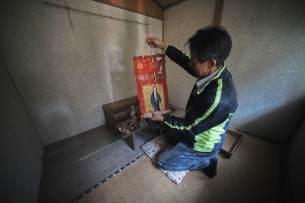 Masatsugu Tanimoto, a farmer and one of the few remaining hidden Christians on Ikitsuki Island, hangs a scroll of the Virgin Mary and Jesus once secretly worshipped at his home in Ikitsuki Island in Hirado, southern Japan, Sunday, April 27, 2025. (AP Photo/Eugene Hoshiko)