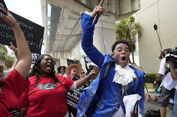 Jonathan Gartwell, right, chants outside of the School Board of Miami-Dade County as part of the "Teach No Lies" march to protest Florida's new standards for teaching Black history, which have come under intense criticism for what they say about slavery, Wednesday, Aug. 16, 2023, in Miami. (AP Photo/Lynne Sladky)