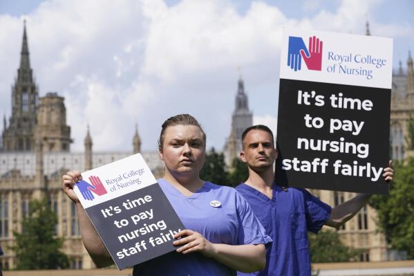 Nurses hold placards outside the Royal College of Nursing (RCN) in Victoria Tower Gardens, London, Wednesday July 21, 2021. In a statement Wednesday July 21, 2021, the British government has tripled its pay increase offer for more than a million National Health Service employees in England, but unions said the proposed boost was insufficient given an anticipated spike in inflation. (Jonathan Brady/PA via AP)