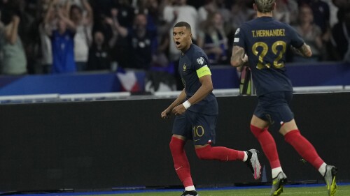 France's Kylian Mbappe, left, celebrates after scoring the opening goal by a penalty shoot during the Euro 2024 group B qualifying soccer match between France and Greece at the Stade de France, outside Paris, Monday, June 19, 2023. (AP Photo/Christophe Ena)