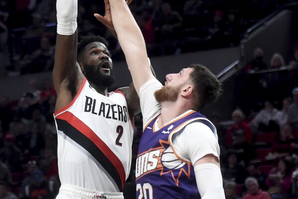 Portland Trail Blazers center Deandre Ayton, left, shoots over Phoenix Suns center Jusuf Nurkic during the second half of an NBA basketball game in Portland, Ore., Tuesday, Dec. 19, 2023. The Blazers won 109-104. (AP Photo/Steve Dykes)
