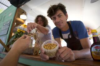 FILE - In this In this Sept. 21, 2014 file photo, Microbar food truck owner Bart Smit holds a container of yellow mealworms during a food truck festival in Antwerp, Belgium. Dried yellow mealworms could soon be hitting supermarket's shelves and restaurants across Europe. The 27 nations of the European Union gave the greenlight Tuesday, May 4, 2021 to a proposal to put the Tenebrio molitor beetle's larvae on the market as a "novel food." (AP Photo/Virginia Mayo, File)