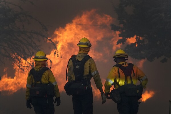 Members of a Los Angeles County Fire crew make a stand to protect a home from the advancing Bobcat Fire along Cima Mesa Rd. Friday, Sept. 18, 2020, in Juniper Hills, Calif. (AP Photo/Marcio Jose Sanchez, File)