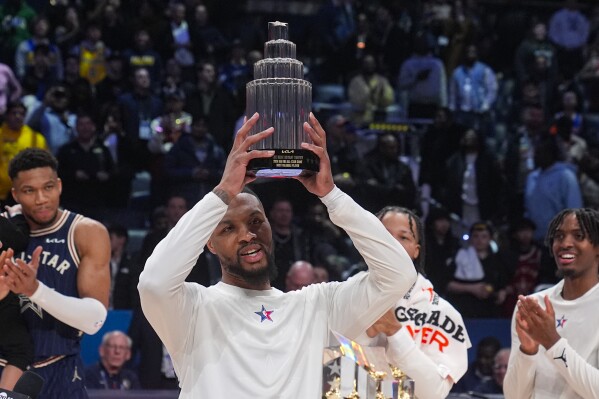 Milwaukee Bucks guard Damian Lillard (0) lifts the MVP trophy after the East defeated the West 211-186 in the NBA All-Star basketball game in Indianapolis, Sunday, Feb. 18, 2024. (APPhoto/Darron Cummings)