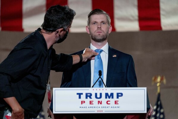 Eric Trump, the son of President Donald Trump, has his tie adjusted before taping his speech for the second day of the Republican National Convention from the Andrew W. Mellon Auditorium in Washington, Tuesday, Aug. 25, 2020. (AP Photo/Andrew Harnik)