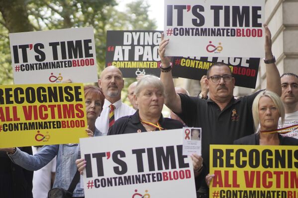 Campaigners, including many who are personally infected and affected by infected blood, hold placards as they gather in Westminster, London, calling for compensation for victims to be authorised by Prime Minister Rishi Sunak, who is giving evidence to the Infected Blood inquiry, Wednesday July 26, 2023. The inquiry was established in 2017 to examine how thousands of patients in the UK were infected with HIV and hepatitis C through contaminated blood products in the 1970s and 1980s. About 2,900 people died in what has been labelled the worst treatment disaster in the history of the NHS. (Jonathan Brady/PA via AP)