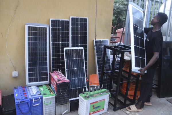 FILE - A man displays solar panels for sale outside a shop in Abuja, Nigeria, June 17, 2023. (AP Photo/Olamikan Gbemiga, File)