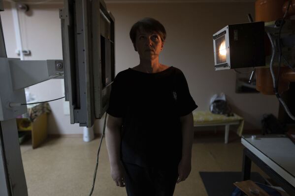 Olena Yahupova stands for an X-ray in a hospital in Zaporizhzhia, Ukraine, Thursday, May 18, 2023. Now safe in Ukrainian territory, Yahupova wants to testify against Russia – for the months it stole from her, the concussion that troubles her, the home she has lost. She still reflexively touches the back of her head, where the bottle struck her over and over. (AP Photo/Evgeniy Maloletka)