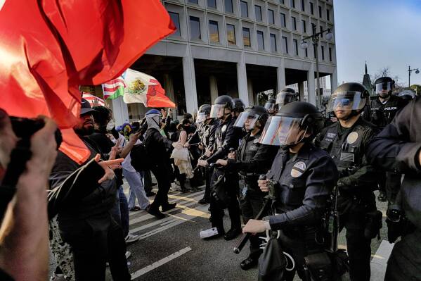 Los Angeles police in riot gear form a skirmish line and push back protesters down a street away from a federal building in downtown Los Angeles on Monday, June 9, 2025. (AP Photo Jae Hong)