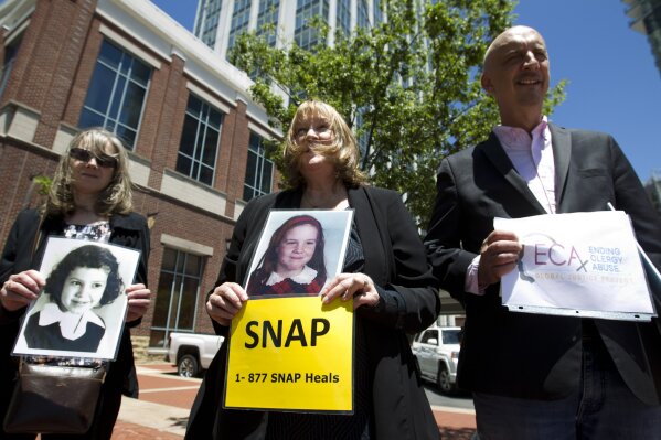 Becky Ianni, center, a victim of priest abuse, holds a picture of her younger self along with other demonstrators outside the venue where the United States Conference of Catholic Bishops 2019 Spring meetings are being held in Baltimore, Tuesday, June 11, 2019.  Ianni says she was 8-years-old when the priest of her family parish began to abuse her. (AP Photo/Jose Luis Magana)